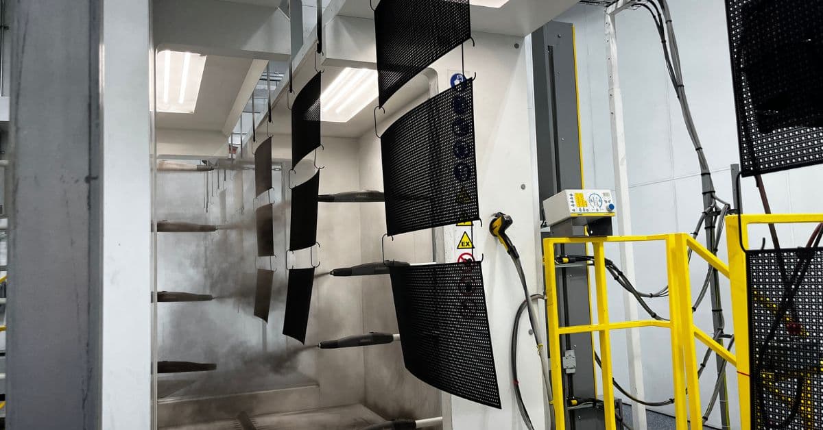 Perforated panels being painted black through a powder coating line